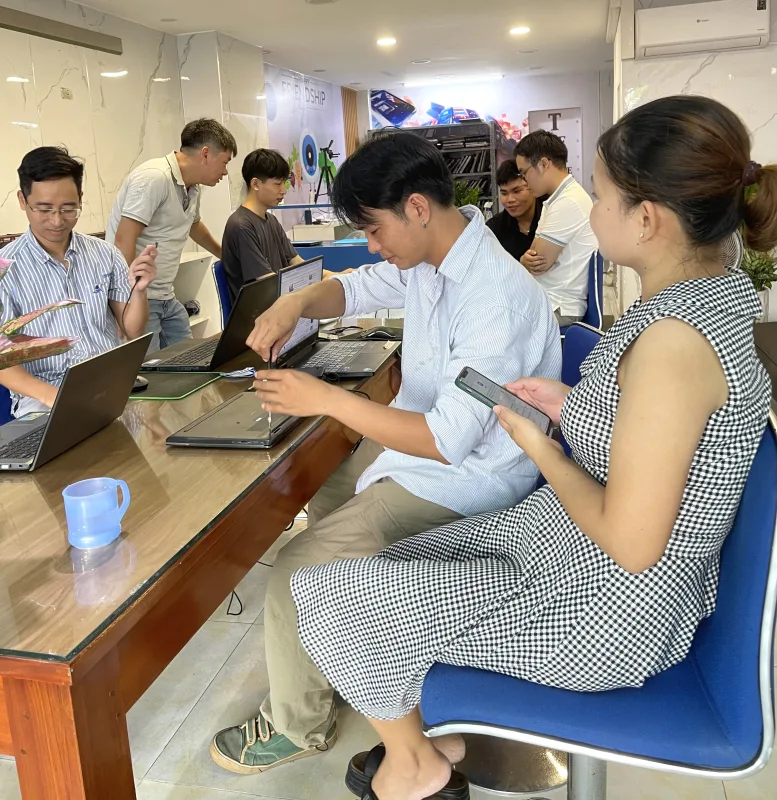 Kỹ thuật viên dùng tua vít tháo máy sửa chữa laptop trên bàn làm việc cùng khách hàng